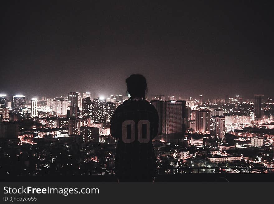 Photo of a Person Watching over City Lights during Night Time