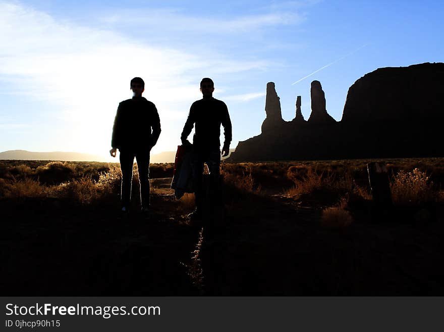 Silhouette of Two Person Standing on the Desert