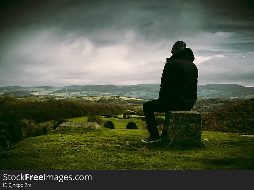 Man in Black Jacket Sitting on Block