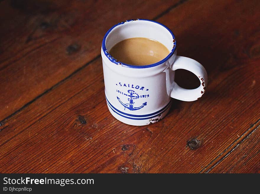 White and Blue Sailor Ceramic Coffee Mug on Brown Wooden Surface