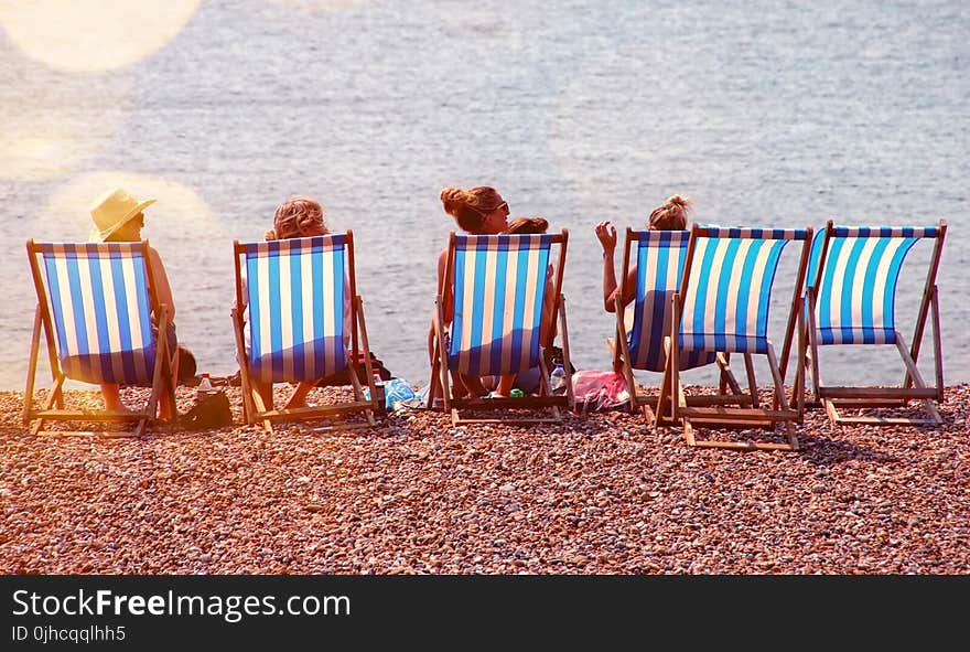 Four People On Lounge Chairs Near The Beach