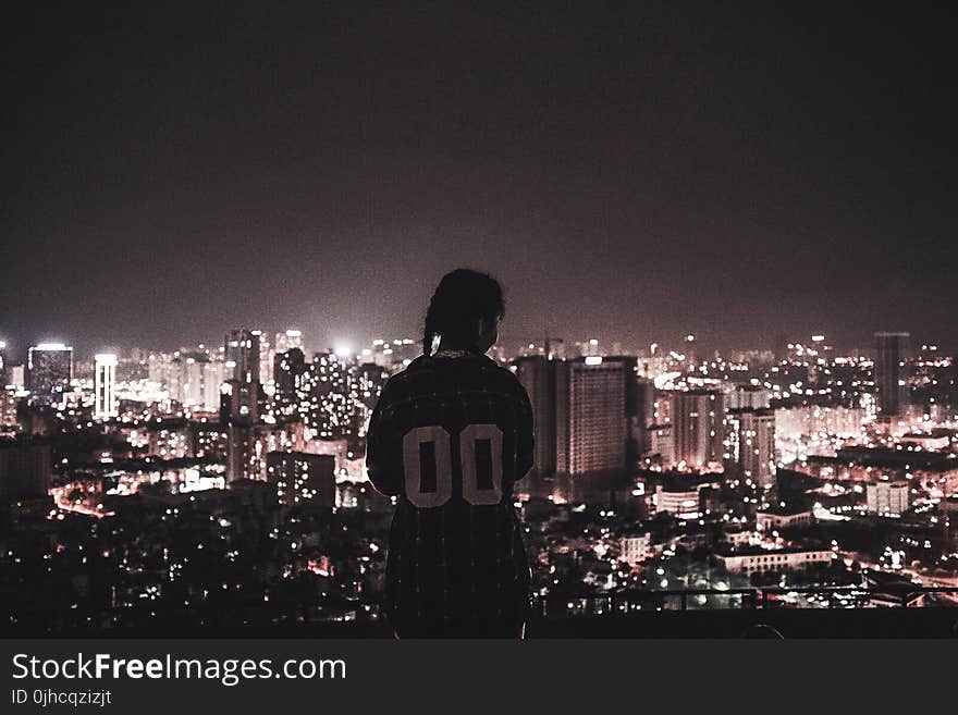 Photo of a Person Watching over City Lights during Night Time