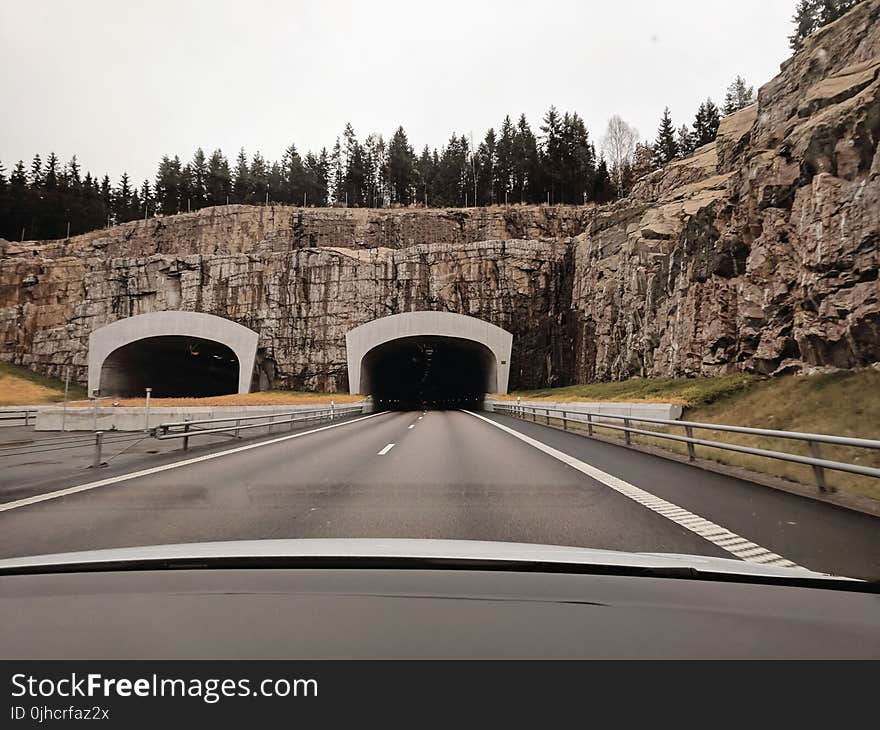 Photo of Two Highway Tunnels in Cliff Under Cloudy Sky