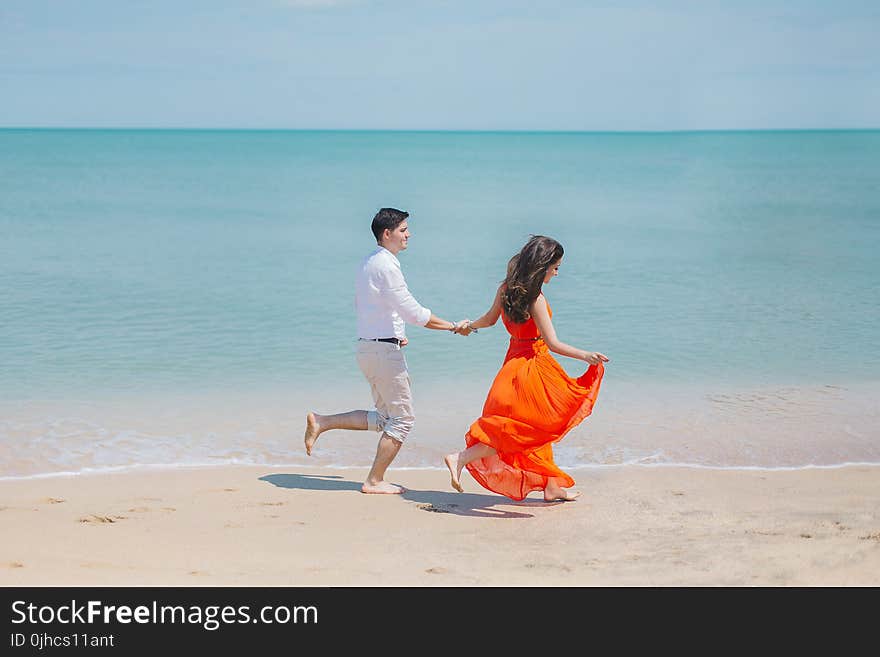 Man and Woman Walks Beside Green Sea