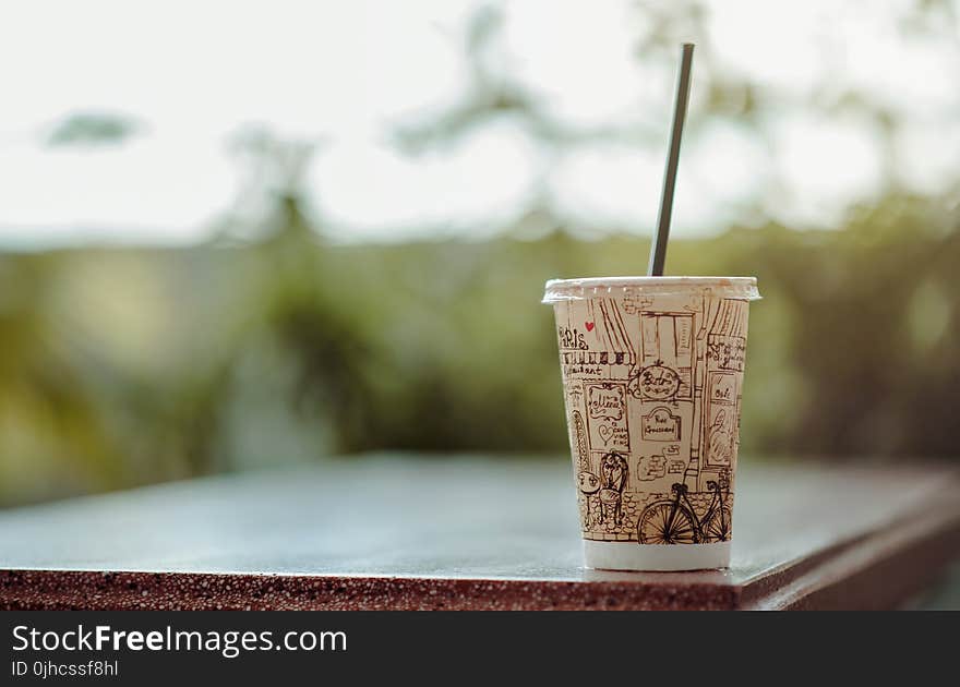 Selective Focus Photo of White Plastic Cup With Lid and Straw