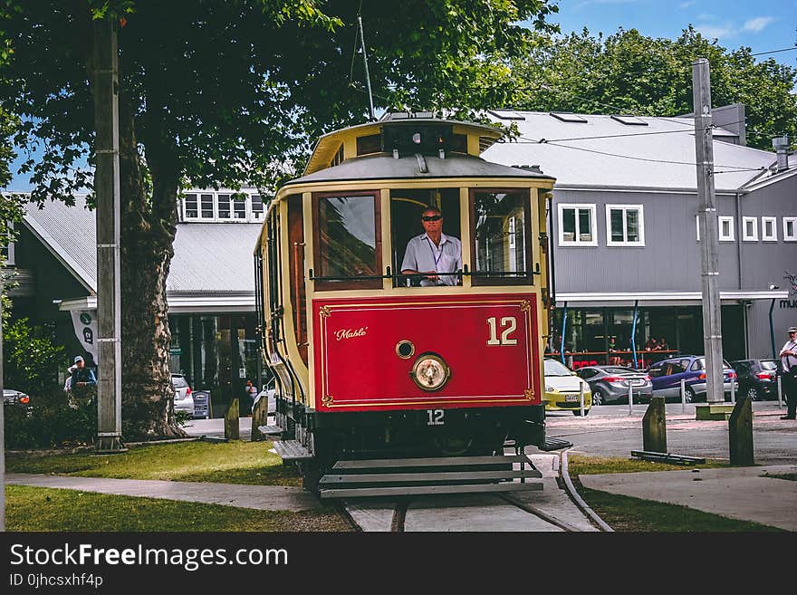 Man Riding on Red and Beige Train