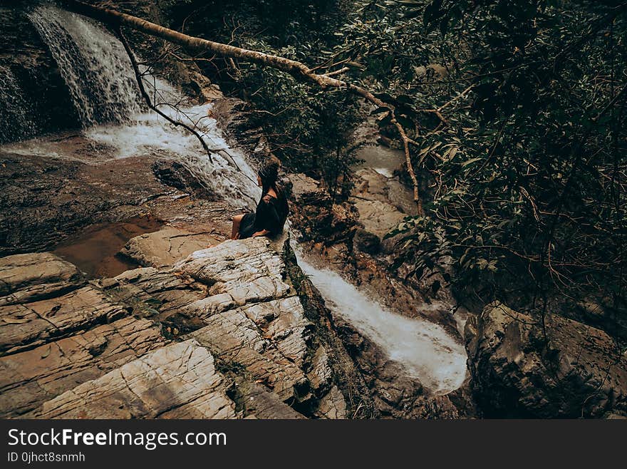 Woman Sitting on Edge Beside Flowing River