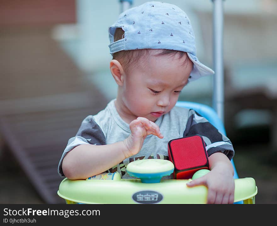 Boy in Gray Crew-neck Shirt Wearing Gray Cap Riding on Yellow and Blue Walker