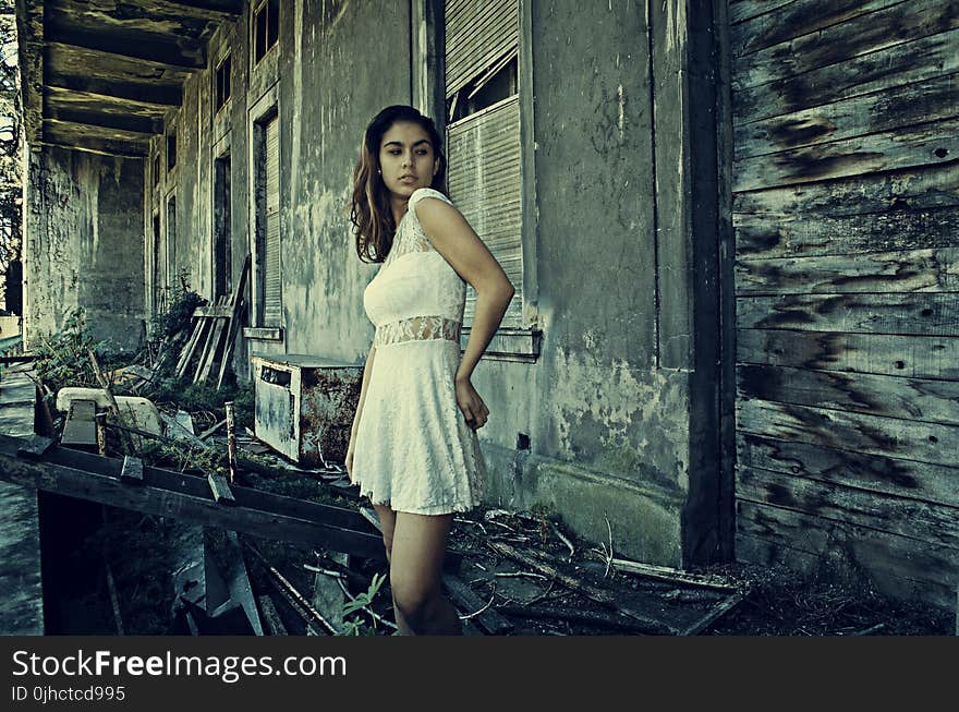 Photo of Woman Wearing White Dress Standing Near Abandoned Building