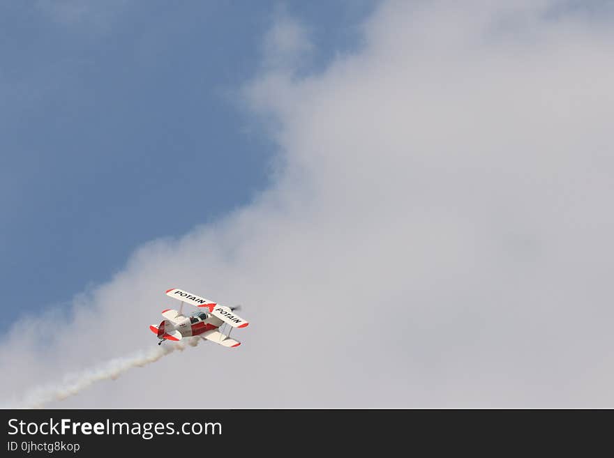 White and Red Biplane Flying during White Cloudy Day