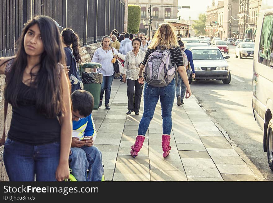 Woman in Black T-shirt, Blue Washed Denim Jeans and Pair of Pink Inline Skates Skating in Street