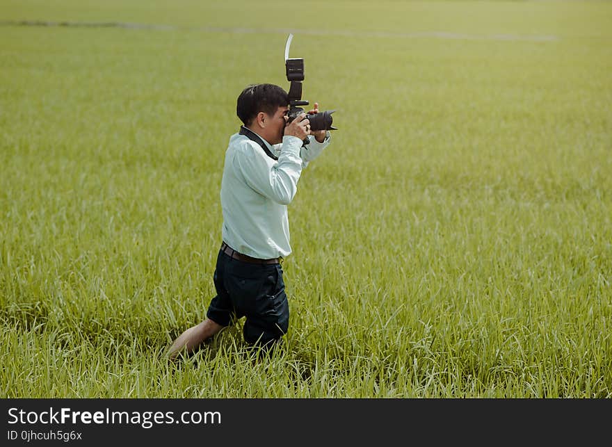 Man Standing on Rice Field Holding Camera