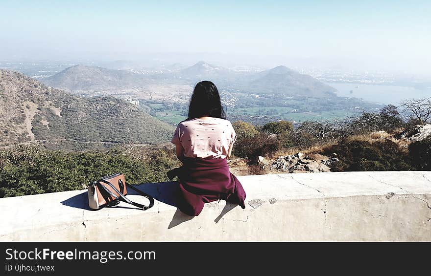 Woman Wearing Pink Shirt Sitting on Gray Concrete Rail