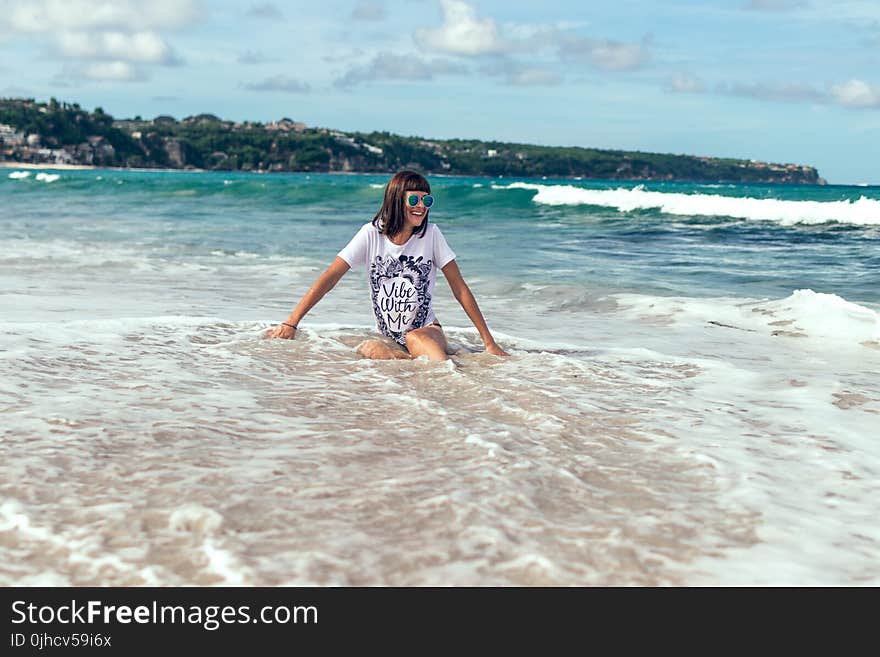 Female Sitting on Beach Shore Wearing White Shirt