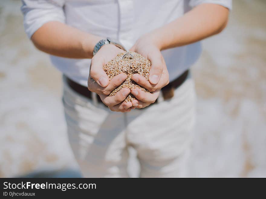 Shallow Focus Photography of Person Holding Brown Sand