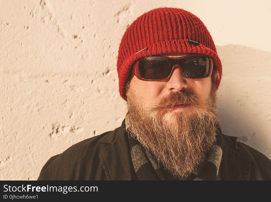 Bearded Man Wearing Red Beanie Cap, Sunglasses ,and Black Jacket