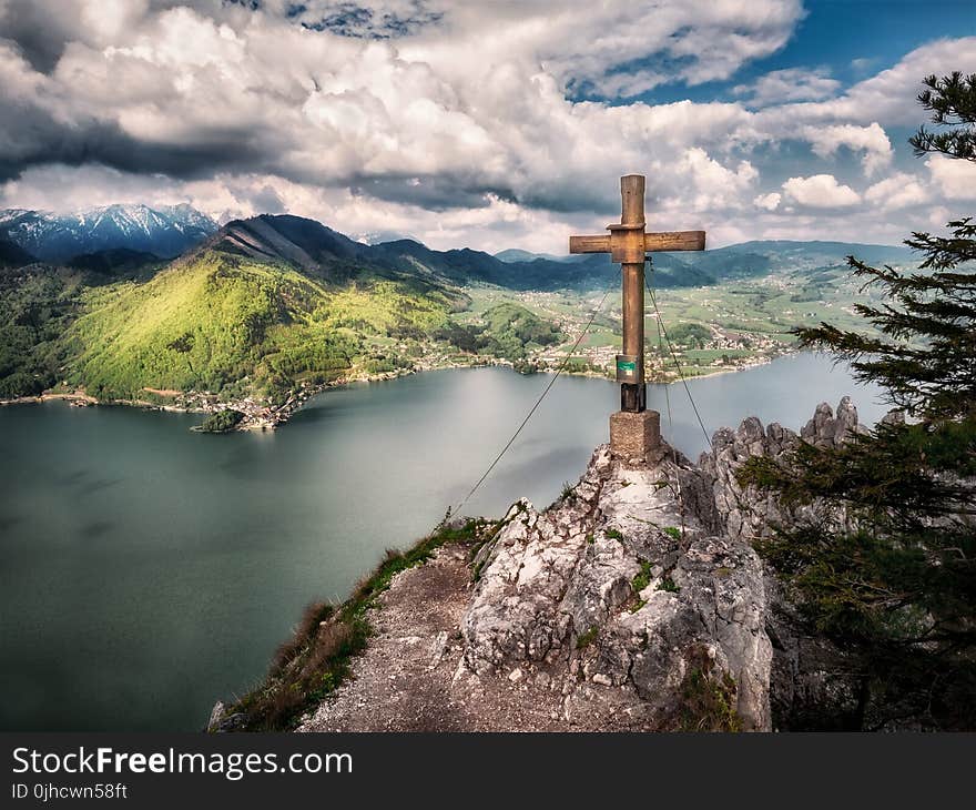 Brown Cross Near Body of Water Under White Sky