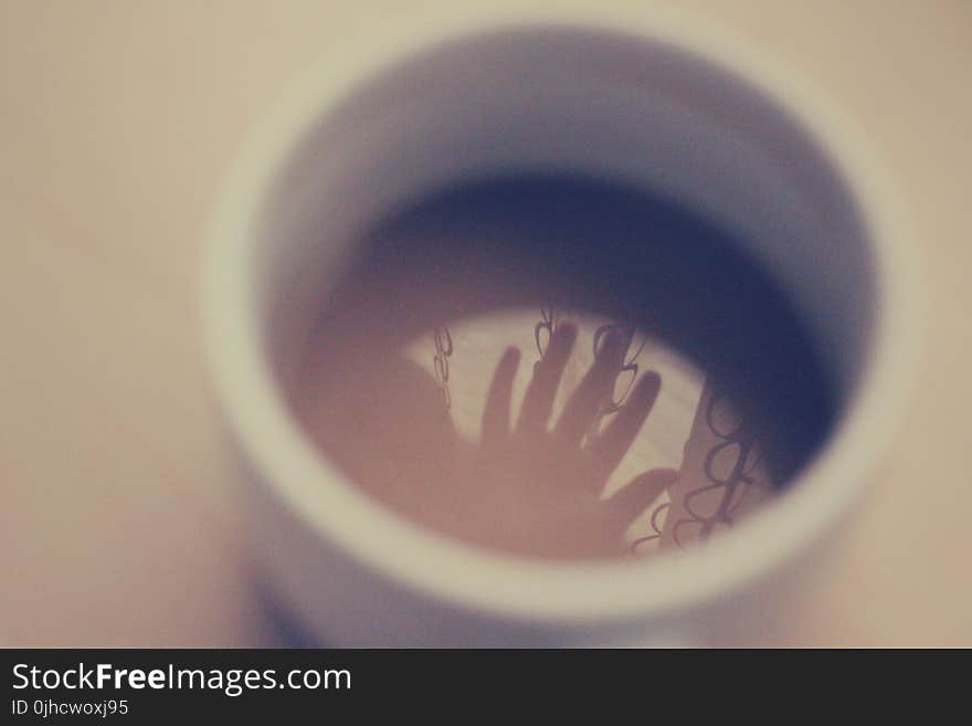 Silhouette of Hand in White Ceramic Cup