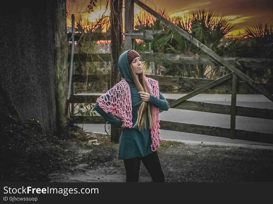 Woman in Green Long-sleeved Dress Standing Near Brown Wooden Fence