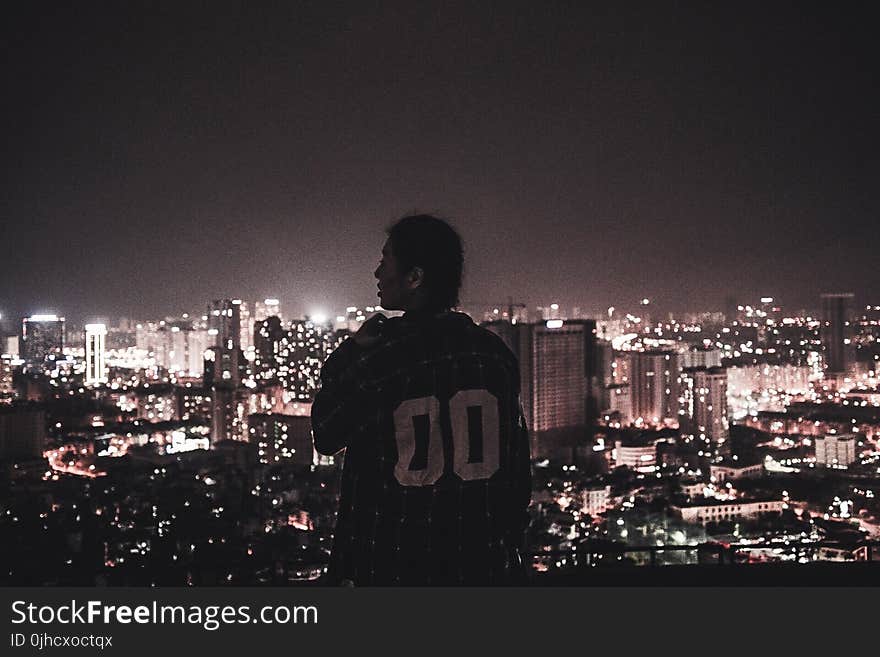 Photography of a Person Watching over City Lights during Night Time