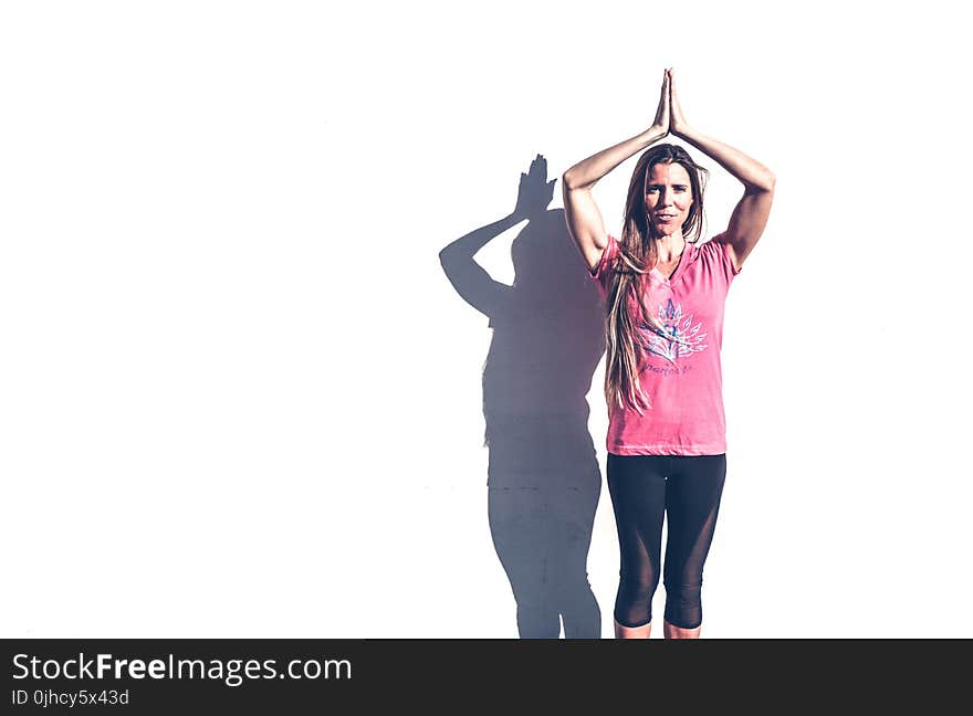 Woman in Pink Crew-neck T-shirt and Black Leggings Standing Near White Wall