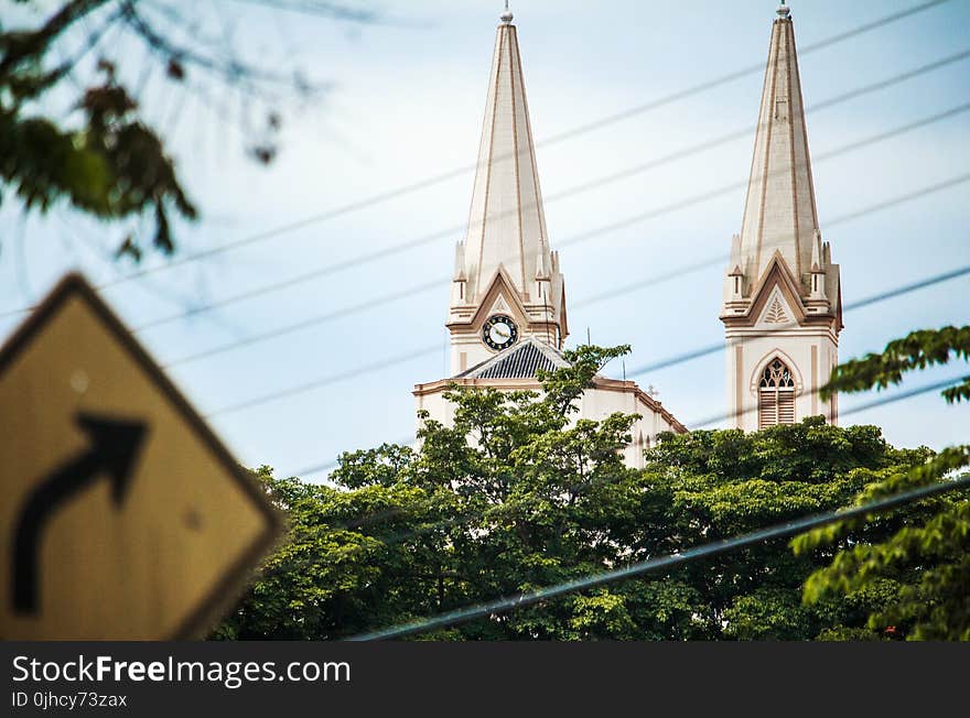 Road Signage Arrow and White Concrete Tower and Green Trees