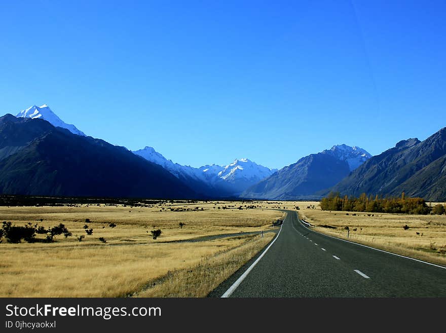 Empty Road Near Mountain Under Blue Skies