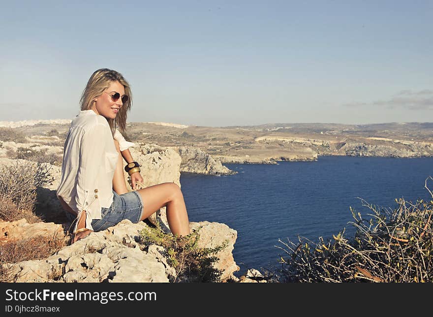 Photo of a Woman Sitting on the Cliff