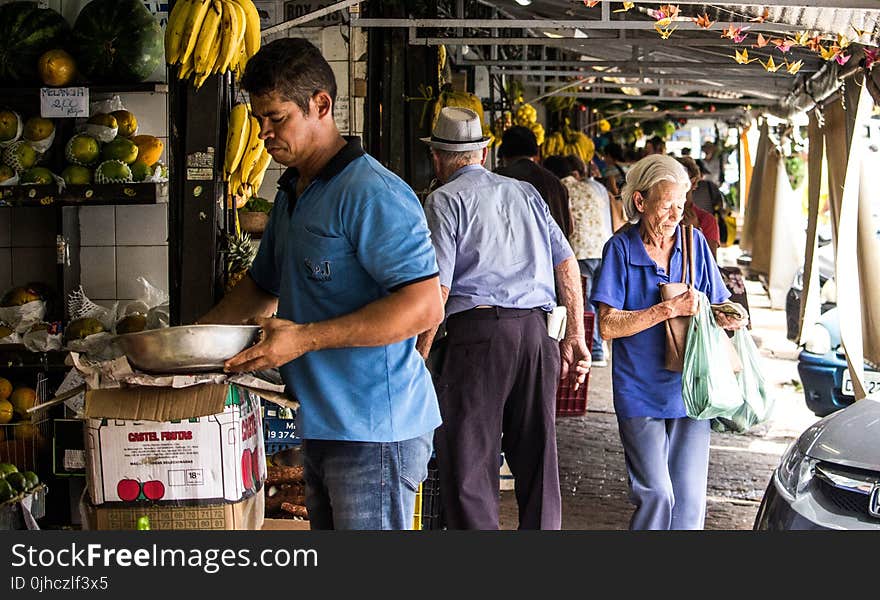 Man Wears Blue Polo Shirt Holding Gray Metal Bowl Near Assorted Fruits