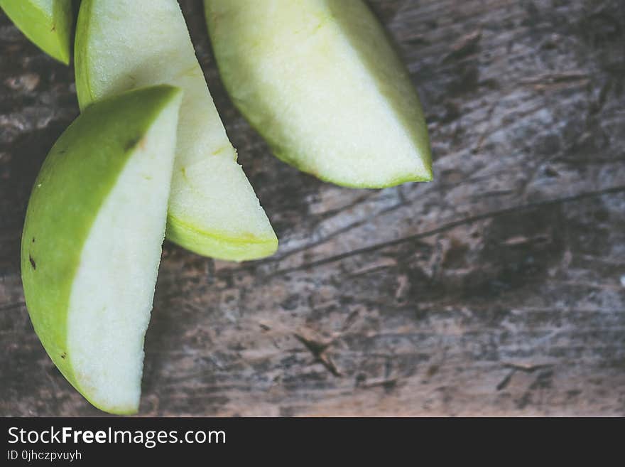 Close-Up Photography of Sliced Green Fruit on Brown Wooden Surface