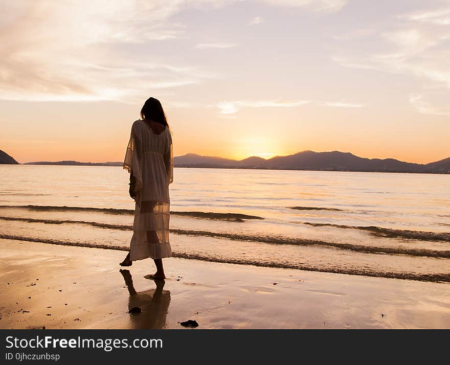 Woman iIn White Dress Walking On Beach