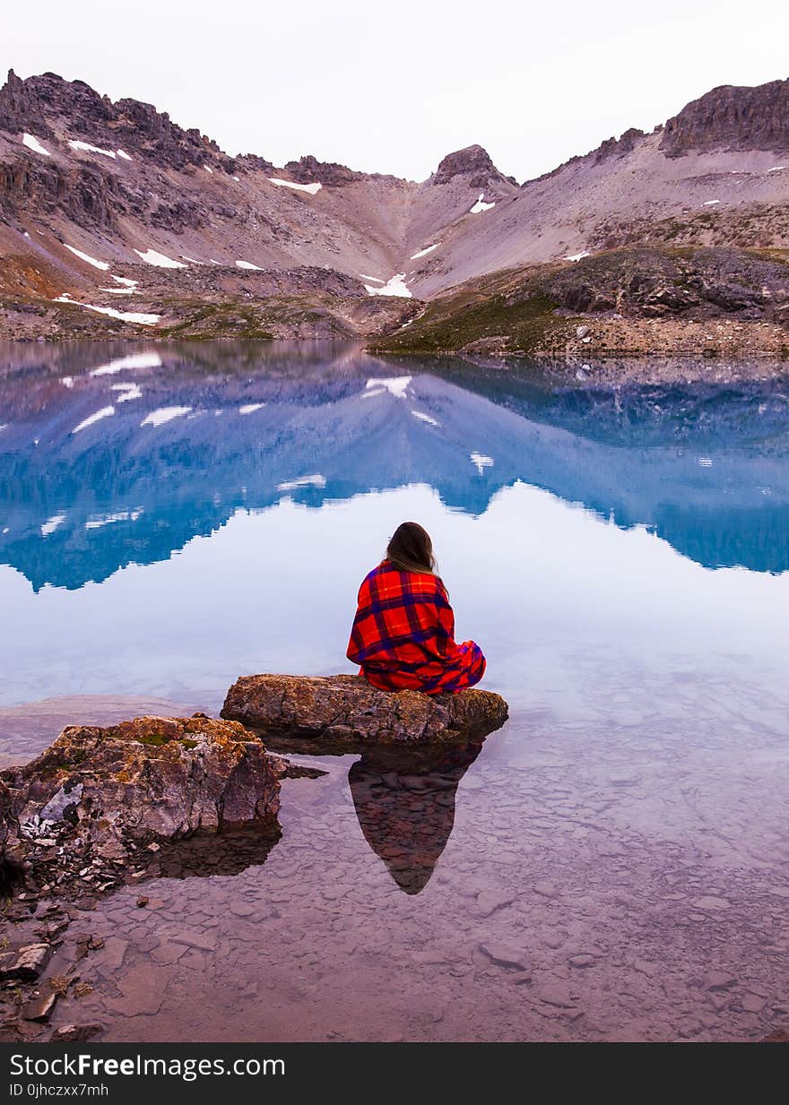 Person Sitting On Rock By The Lake