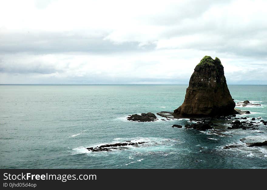 Photo of Brown Rock Formation in Body of Water