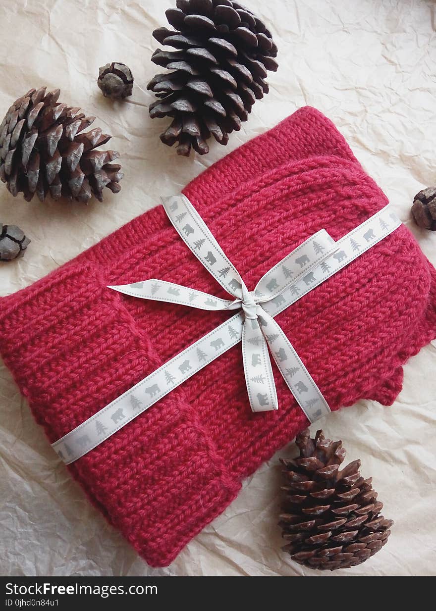 Red Knitted Textile And Three Black Pine Cones