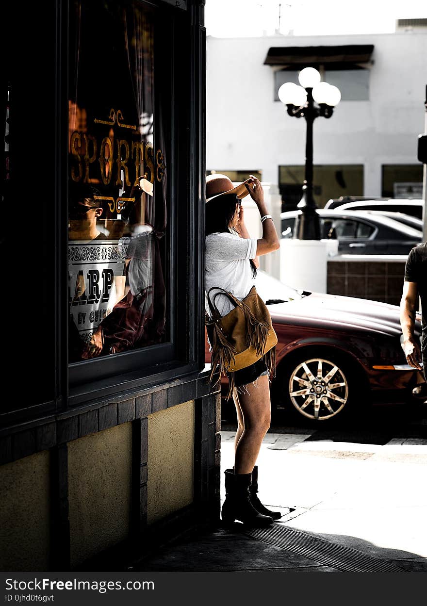 Woman in Brown Sunhat Standing on Sidewalk