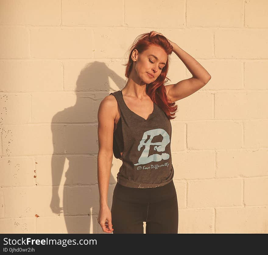 Woman in Gray and Black Tank Top Standing Near Wall