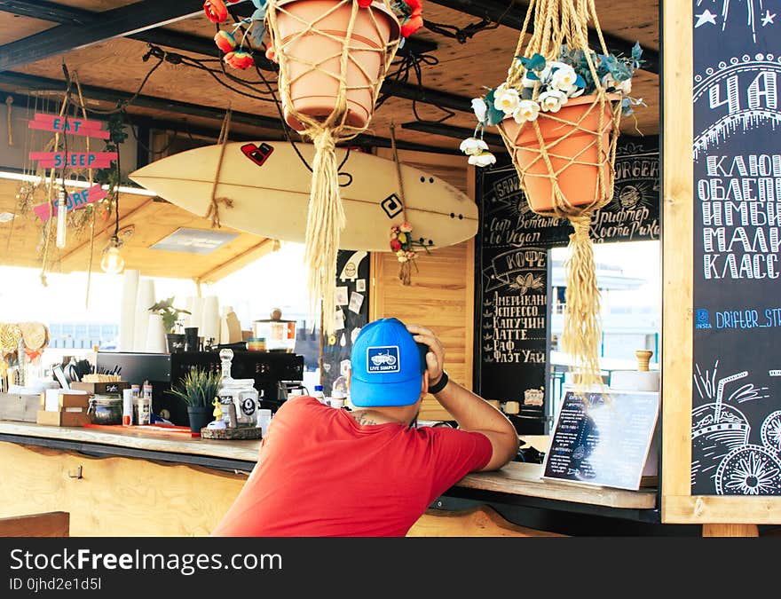 Man Near Counter Desk With Hanging Surfboard