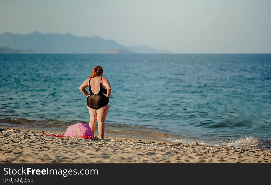 Photography of a Woman in Black Swimsuit Standing on the Seashore