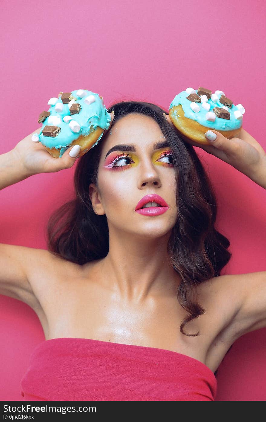 Woman in Red Tube Top Holding Two Doughnuts