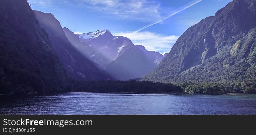 Body Of Water Near Mountain Under Clear Sky