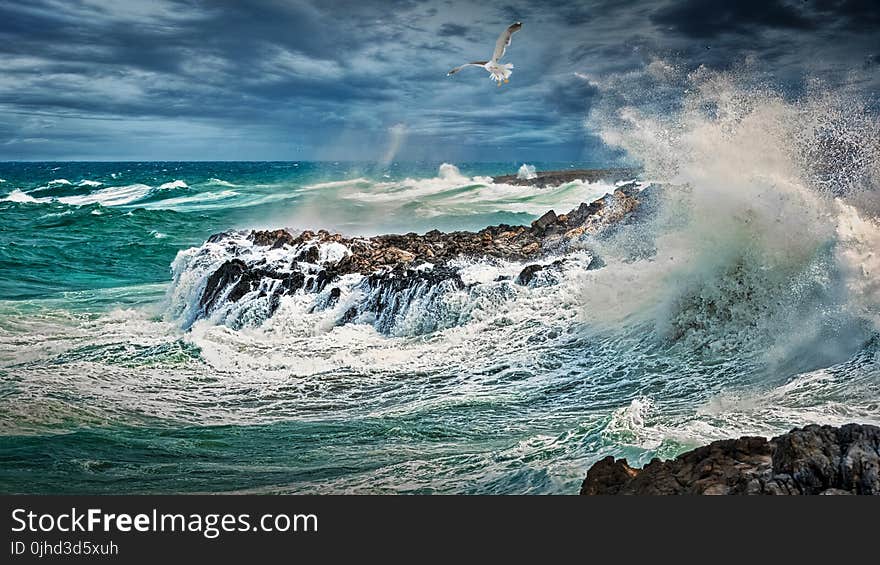 Beach Beside Stone Formation With Waves at Daytime