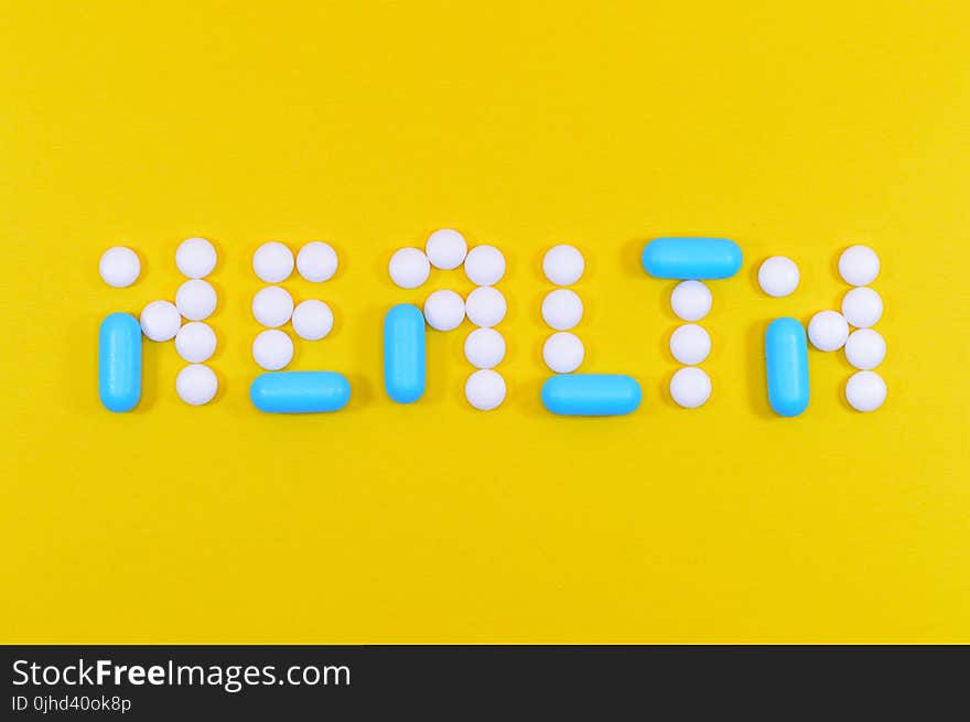 White and Blue Health Pill and Tablet Letter Cutout on Yellow Surface