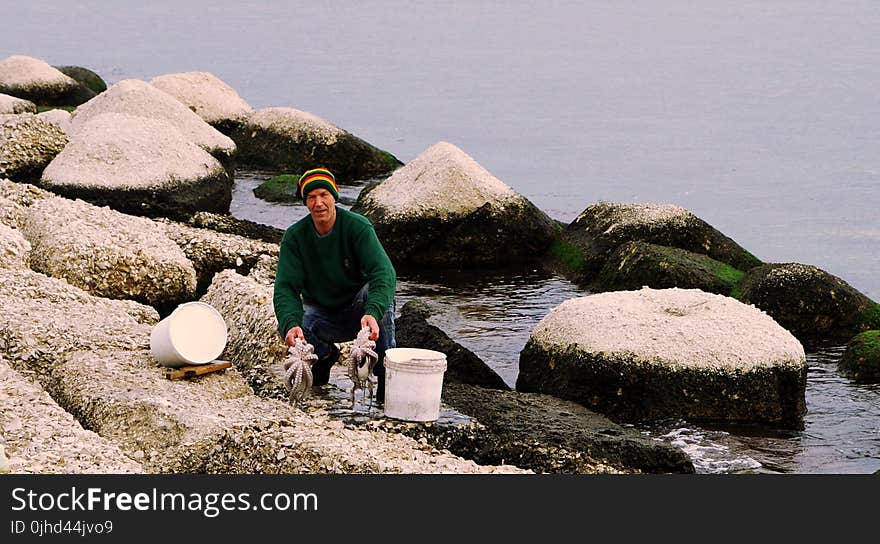 Photography of a Man Holding Two Octopus