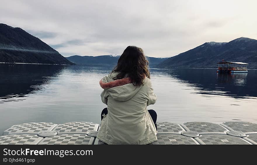 Woman Wearing Gray Jacket in Front of Body of Water