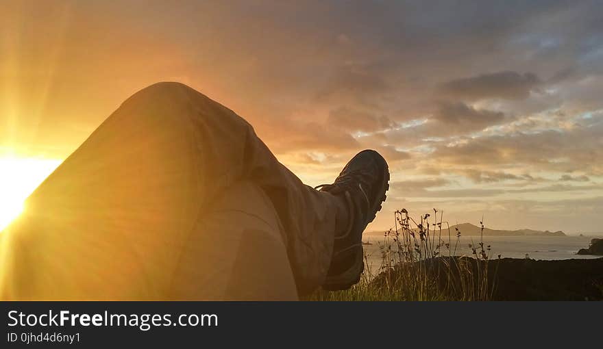 Sun Reflecting on Person Cross Leg Under Cumulus Clouds during Sunrise