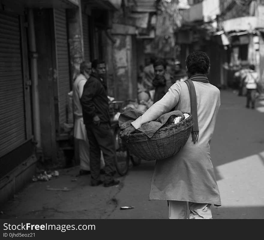 Grayscale Photo of Woman Carrying Basket