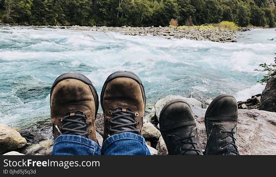 Person in Brown Boots Near Body of Water at Daytime