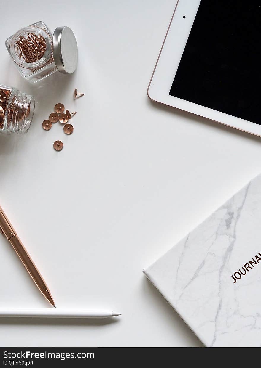 White Ipad On The Table Near Small Clear Glass Jars