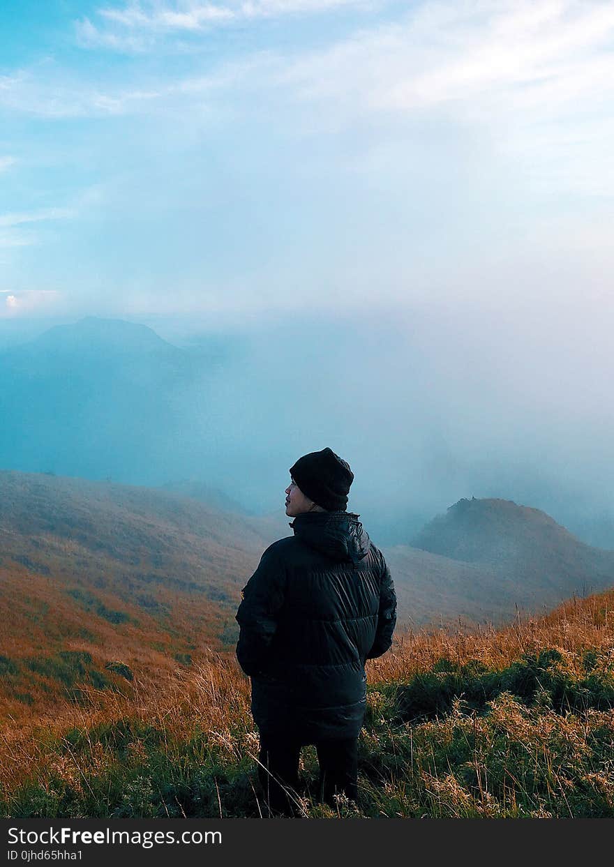 Man in Black Jacket Standing on Mountain With Fog