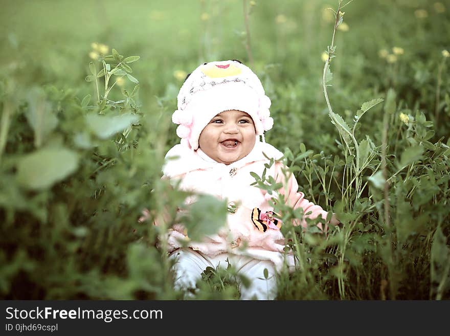 Toddler Wearing Whit Cap on Green Field